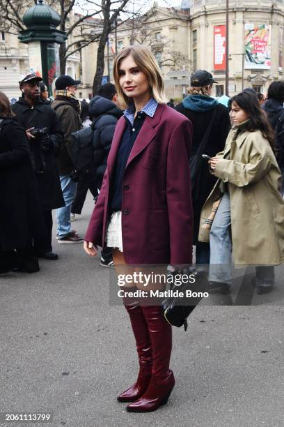 Xenia Adonts is seen wearing a bordeaux Miu Miu jacket, a blu Miu Miu sweater, a white skirt, a black Miu Miu bag and bordeaux leather boots outside...