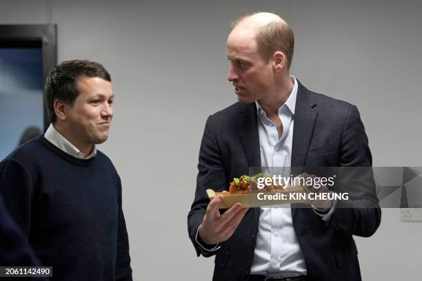 Britain's Prince William, Prince of Wales speaks to Pierre-Yves Paslier founder of Notpla as he holds a sustainable seaweed-based food plate during a...