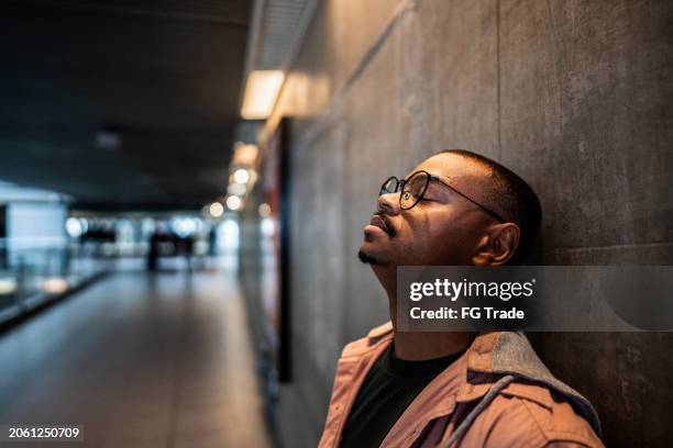 sad mid adult man at subway station - vorurteil stock-fotos und bilder