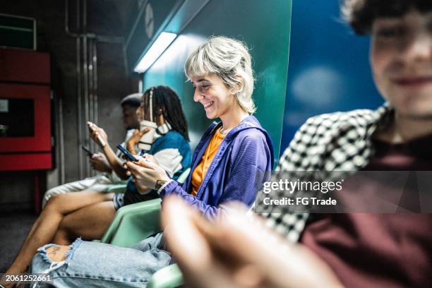 jeune femme utilisant un téléphone portable sur le quai du métro - gare ferroviaire photos et images de collection