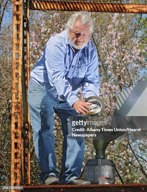 Larry Syzdek, an aerobiologist who counts pollen for a national database, uses a scientific vacuum called a Burkard at his pollen station at his farm...