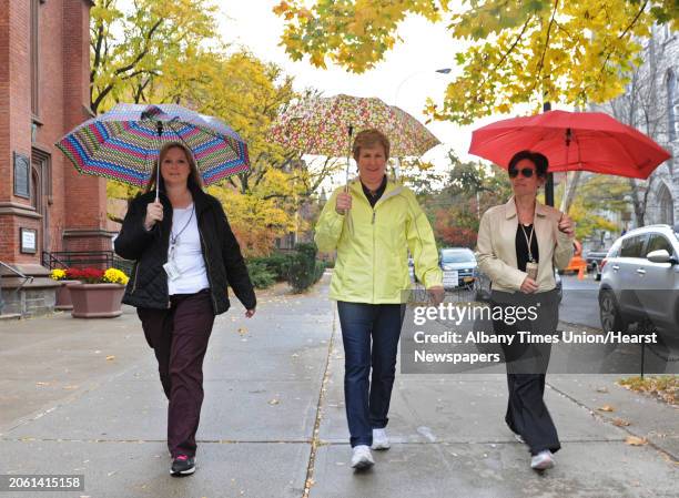 From left, DEC employees Amy KcKelvey of Rotterdam, Sandra King of Saratoga Springs and Maryann Mroz of Colonie use their umbrellas as they walk down...