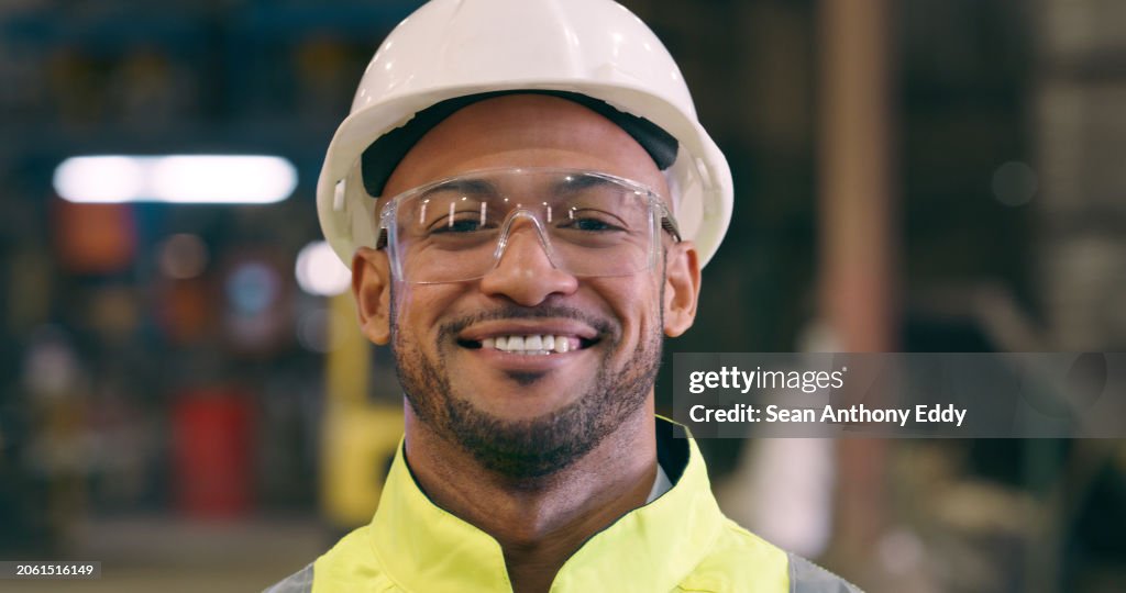 Hombre, retrato y gafas de seguridad para ingeniero en taller, construcción o mantenimiento con sonrisa. Fabricación, producción e ingeniería con gafas para protección, fábrica con mano de obra y casco