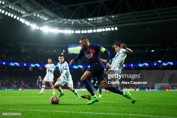 Kylian Mbappe of Paris Saint-Germain is challenged by Takefusa Kubo of Real Sociedad during the UEFA Champions League 2023/24 round of 16 second leg...