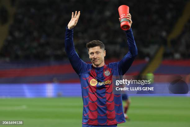 Barcelona's Polish forward Robert Lewandowski waves as he holds La Liga Best Player of the Month trophy before the Spanish league football match...