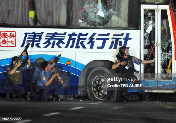 Philippine policemen take position as they start their attack on the tourist bus hijacked in Manila on August 23, 2010. An ex-policeman armed with a...