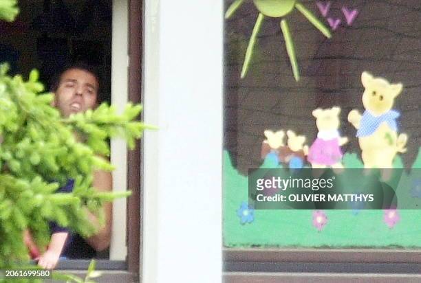 The hostage-taker looks from a window of a day care in Wasserbillig, Luxembourg, 01 June 2000. The armed man holds 25 children and three adults...