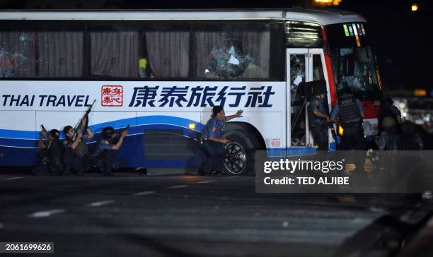 Philippine policemen take position as they start their attack on the tourist bus hijacked in Manila on August 23, 2010. An ex-policeman armed with a...
