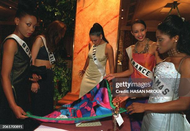 Miss France, Sonia Rolland , shows other Miss Universe contestants her country's present, a silk scarf with a print of a painting by Pablo Picasso,...