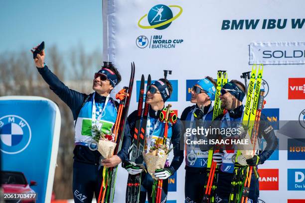 Italy's Tommaso Giacomel takes a selfie with Didier Bionaz, Lukas Hofer, and Patrick Braunhofer to celebrate their team's second-place finish in the...