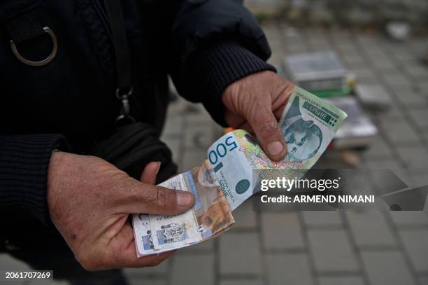 Street vendor shows Serbian Dinar banknotes in the town of Gracanica, central Kosovo on March 1, 2024. Serb communities in parts of Kosovo were...