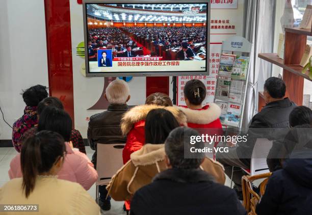 People watch a television showing the live broadcast of the opening meeting of the second session of the 14th National People's Congress on March 5,...