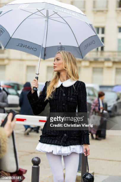 Tatiana Korsakova with umbrella wears black white dress, tights, round bag outside Chanel during the Womenswear Fall/Winter 2024/2025 as part of...