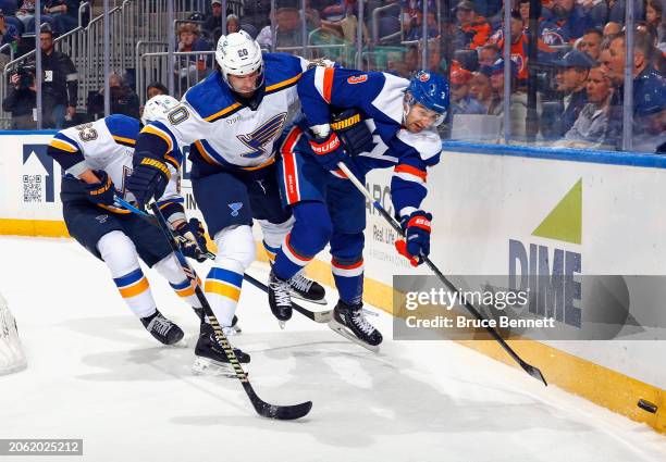 Brandon Saad of the St. Louis Blues bumps Adam Pelech of the New York Islanders off the puck during the first period at UBS Arena on March 05, 2024...