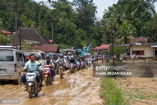 Motorists drive through a muddy road following flash flooding in Pesisir Selatan Regency, West Sumatra on March 9 after days of heavy rain across the...