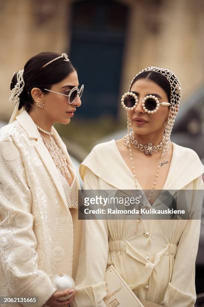 Twins Jyoti Babani, Snehal Babani wears glasses decorated with pearls and crystals, head and hair accessories, and a creme white blazer outside...