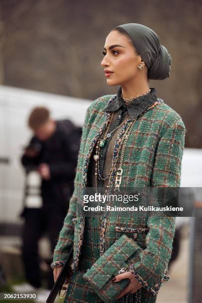 Guest wears green hijab or a head scarf, green checkered blazer, flared green pants, Chanel necklaces and a bag outside Chanel during the Womenswear...