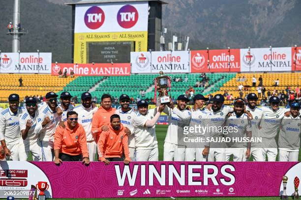 India's players pose with the series trophy after winning the fifth and last Test cricket match between India and England at the Himachal Pradesh...