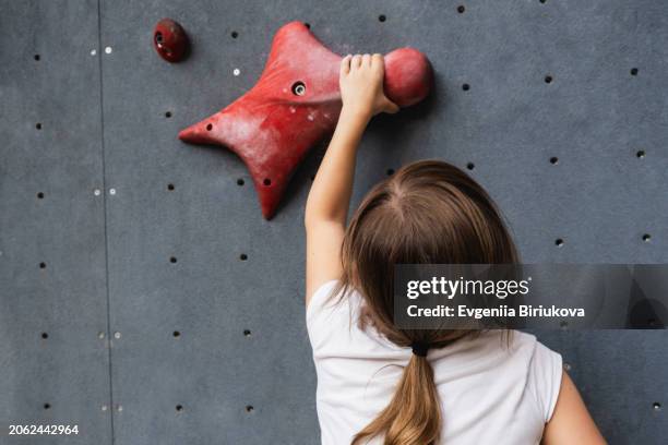 the children's hand holds a climbing hook on home climbing wall - bouldering stock pictures, royalty-free photos & images