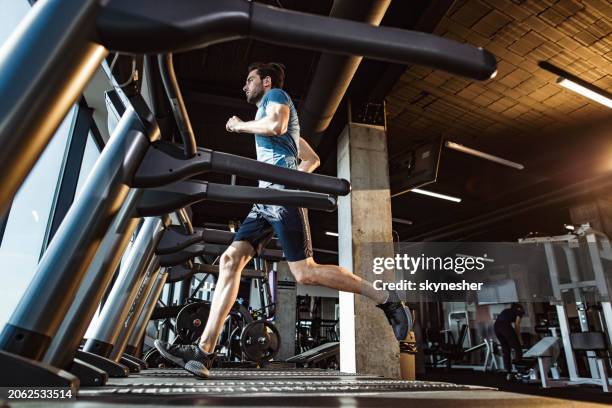 below view of athletic man jogging on treadmill in a gym. - exercise machine stock pictures, royalty-free photos & images