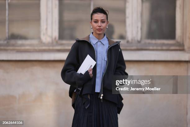 Fashion Week Guest seen wearing a denim long jeans skirt, babyblue and white stripped blouse, grey sweater jacket and silver earrings outside Sacai...