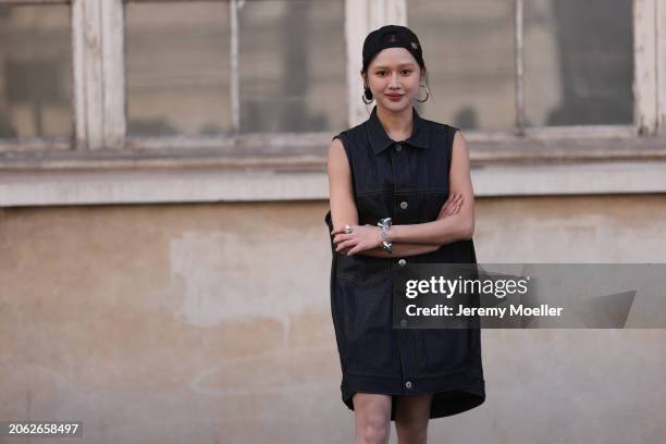 Fashion Week Guest seen wearing a denim jeans vest dress, black bralette, black socks, black leather boots and a black cap and silver necklace and...