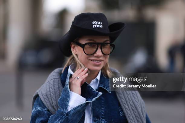 Karin Teigl seen wearing Miu Miu black denim logo cowboy hat, black aviator glasses, Miu Miu light blue striped buttoned shirt, Miu Miu grey cable...