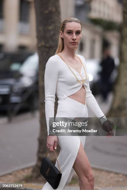 Magda Swider seen wearing S.O.T.S Apparel white long dress with cut-outs and golden chains, Saint Laurent black leather bag and Cartier Trinity...