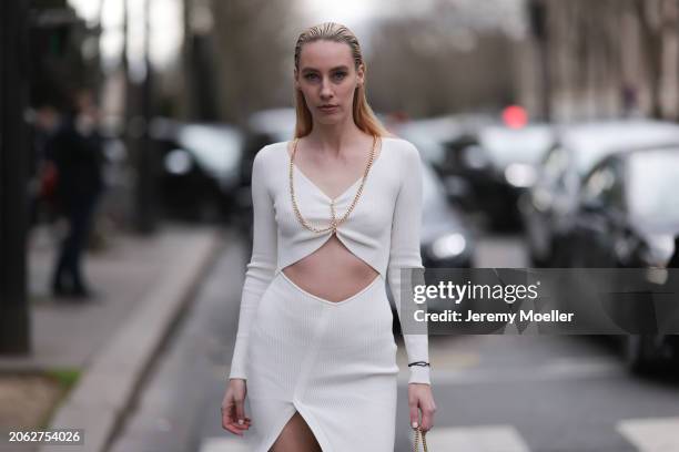 Magda Swider seen wearing S.O.T.S Apparel white long dress with cut-outs and golden chains and Cartier Trinity bracelet, before Miu Miu, during the...