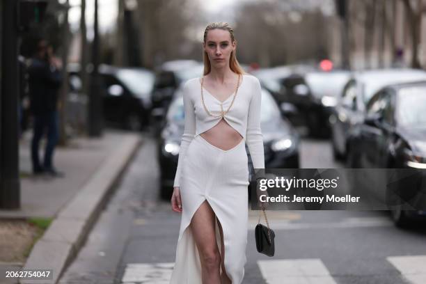 Magda Swider seen wearing S.O.T.S Apparel white long dress with cut-outs and golden chains, Saint Laurent black leather bag and Cartier Trinity...