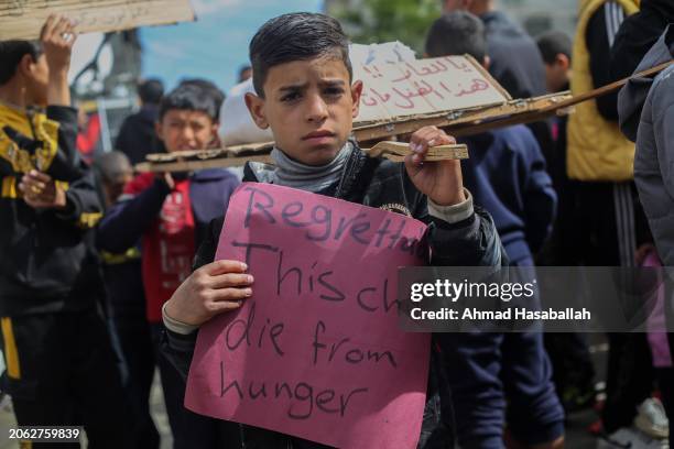 Palestinian children carry banners during a march demanding an end to the war and an end to the famine that citizens suffer from due to the war on...