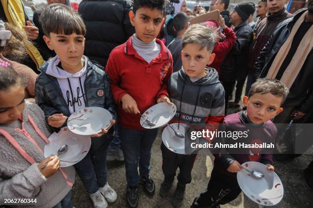 Palestinian children carry empty bowls during a march demanding an end to the war and an end to the famine that citizens suffer from due to the war...