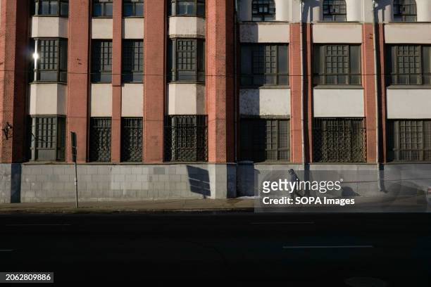 Lonely passerby near the facade of a Soviet monumental building on Zemlyanoy Val Street in early spring Moscow.