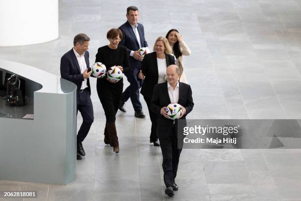 German Chancellor Olaf Scholz arrives with the official match ball with government ministers to mark the 100-day countdown to the opening game of...