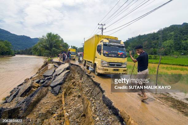 Man guides a truck along an erosion-damaged road following flash flooding in Pesisir Selatan Regency, West Sumatra on March 9 after days of heavy...