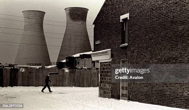 Snow Covered Ground Man Walking Past Derelict House East, London, With cooling towers in the Background, London 1980s.