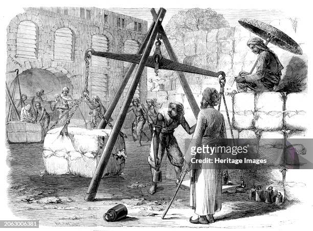 Weighing cotton at Bombay for the English market, 1862. Here '...the bales are landed from Surat, Baroche, Cambay, and other parts of Guzerat,...