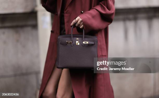 Leonie Hanne seen wearing a dark red long trenchcoat, red shirt, black leather skirt, belt, Hermes Birkin handbag outside Hermes show, during the...