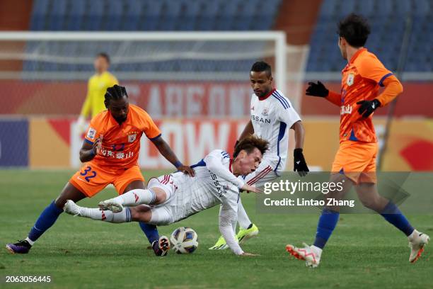 Asahi Uenaka of Yokohama F.Marinos is tripped up by Fei Nanduo of Shandong Taishan during the first half of the AFC Champions League quarter final...