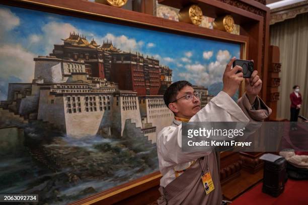Tibetan journalist takes photos in front of a painting of the Potala Palace in Lhasa, at the Tibet delegation meeting of the National Peoples...
