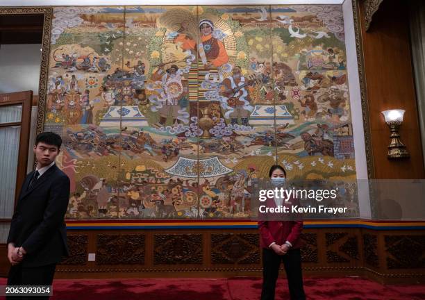 Hostess and security guard, left, stand in front of a painting at the Tibet delegation meeting of the National Peoples Congress at the Great Hall of...