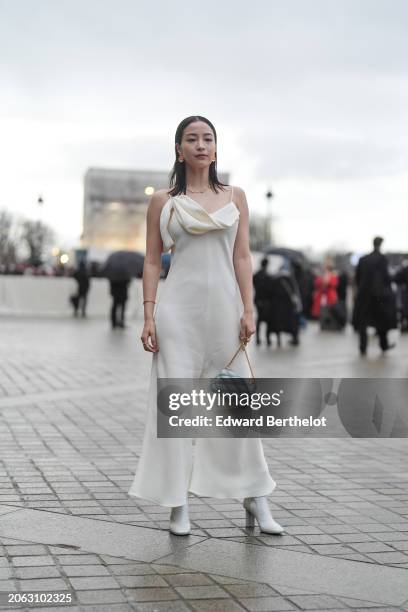 Suzu Hirose wears a white jumpsuit with flared pants , a blue embossed leather bag, high heels pointed boots, outside Louis Vuitton, during the...