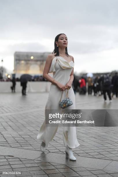 Suzu Hirose wears a white jumpsuit with flared pants , a blue embossed leather bag, high heels pointed boots, outside Louis Vuitton, during the...