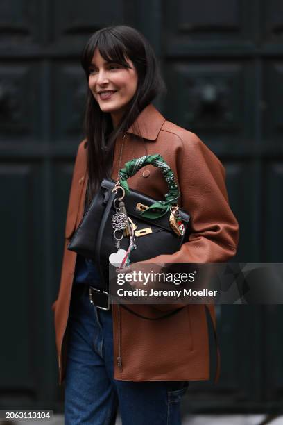 Leia Sfez is seen wearing a brown leather Hermes jacket, blue denim jeans, black belt and Hermes black bag with Kelly twilly charms outside Hermes...