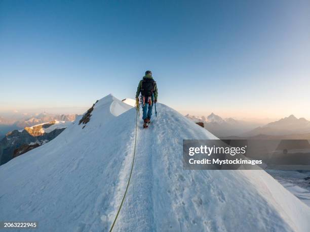 alpinist aiming for the summit on snowy ridge - montanhismo imagens e fotografias de stock