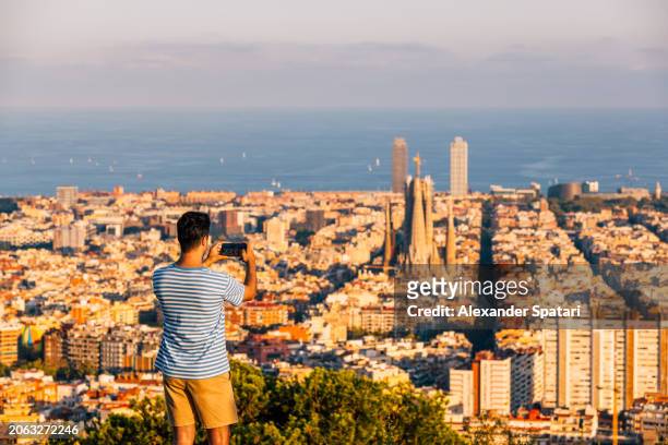 man taking photo of barcelona skyline with sagrada familia at sunset, spain - barcelona cityscape stock pictures, royalty-free photos & images