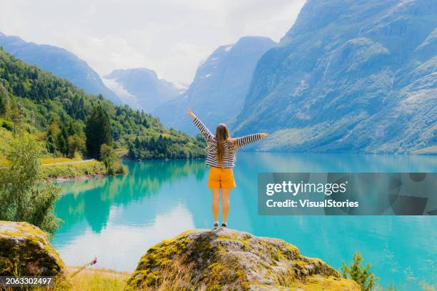 woman tourist admiring summer with scenic view of lake lovatnet in norway - hygge stockfoto's en -beelden