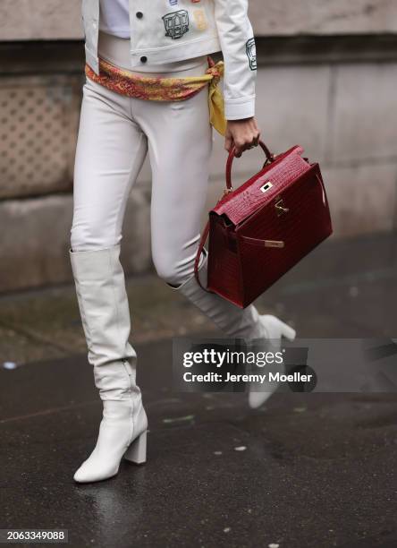 Fashion Week Guest seen wearing a white two piece outfit, white leather jacket, white pants, yellow and orange Hermes scarf, white leather boots and...