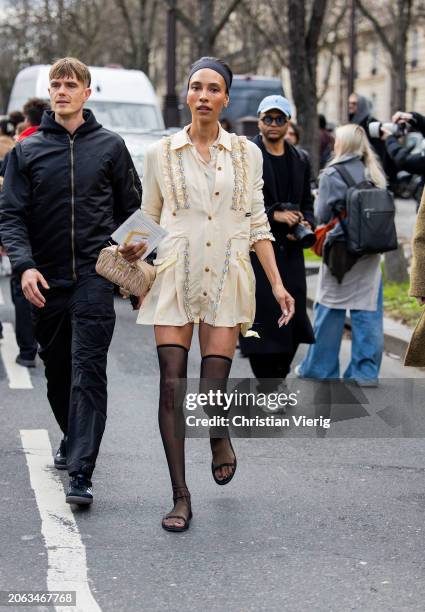 Guest wears black head band, beige button shirt, bag, over knee tights outside Miu Miu during the Womenswear Fall/Winter 2024/2025 as part of Paris...