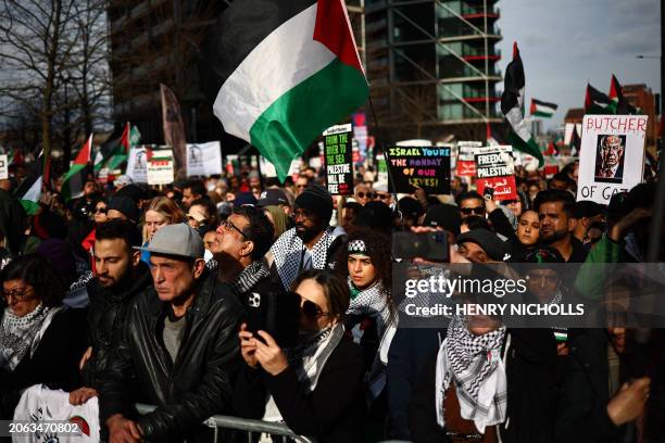 Pro-Palestinian activists and supporters wave flags and hold placards as they gather near the US Embassy following a march through London, during a...